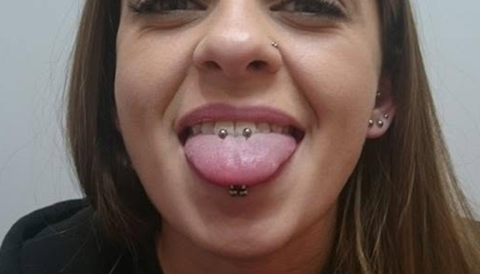 Femme portant un piercing de langue et un labret vertical chez Atyka Body Works à Toulouse