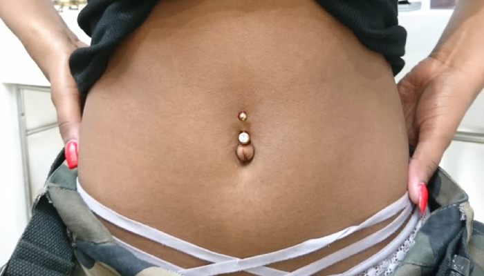 Femme portant un piercing du nombril avec bijou doré chez Atyka Body Works à Toulouse