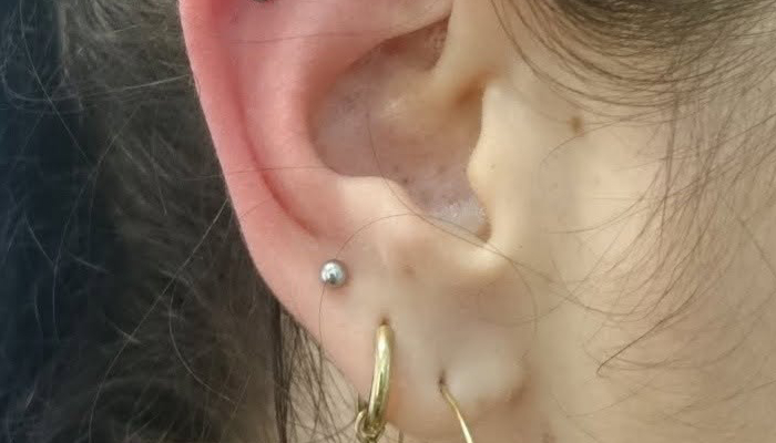 Oreille portant un micro-piercing discret au lobe avec bijou argenté chez Atyka Body Works à Toulouse