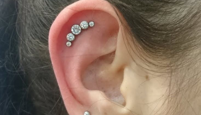 Oreille avec piercing hélix composé de plusieurs bijoux brillants chez Atyka Body Works à Toulouse