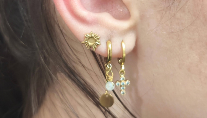 Oreille avec plusieurs piercings du lobe ornés de bijoux dorés chez Atyka Body Works à Toulouse