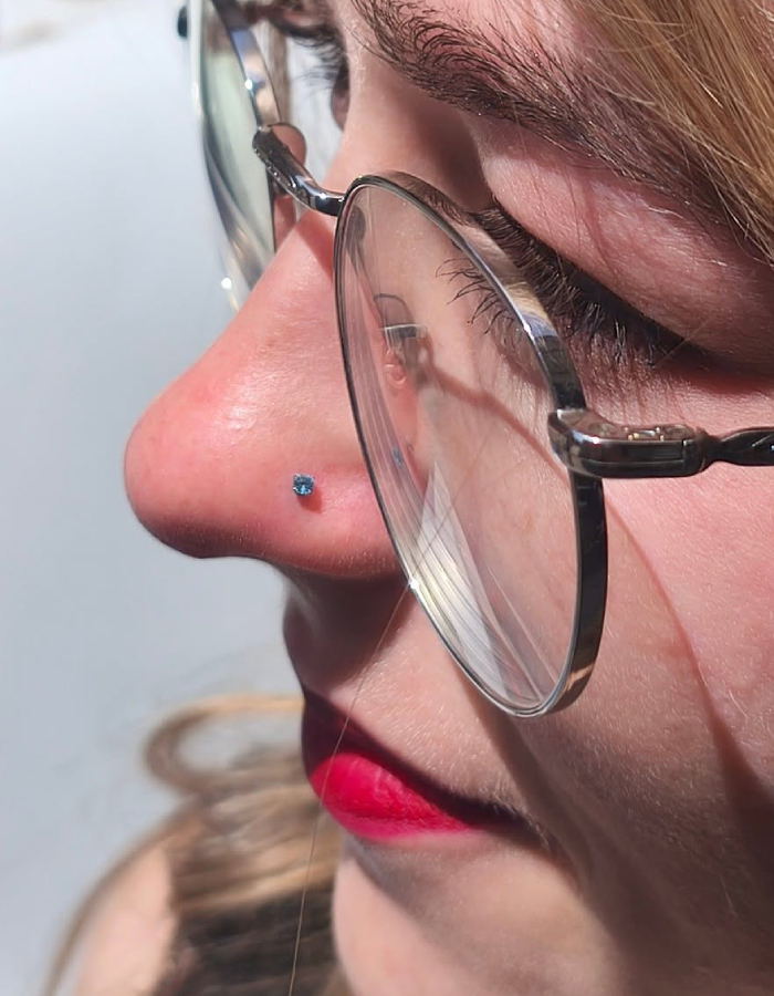 Micro-piercing du nez avec bijou bleu à Toulouse Femme portant un micro-piercing discret avec bijou bleu sur le nez chez Atyka Body Works à Toulouse